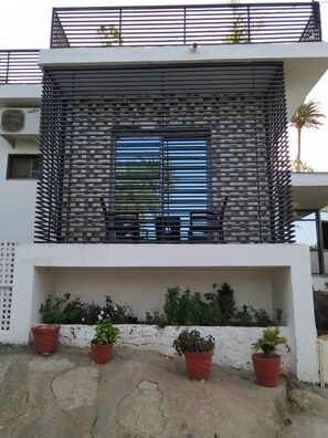 A modern building with a balcony, potted plants, and a metal fence. - Mohan Villa Home Stay (Abu Road)