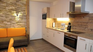 A compact kitchen with a built-in oven, microwave, and wooden accents. - Landhaus & Haus Rustika (Wagrain)