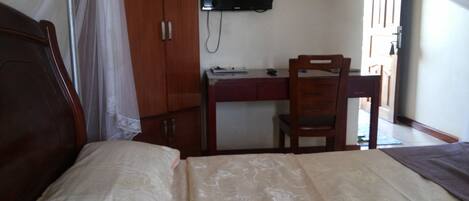 A bedroom with a bed, a desk, and a chair.