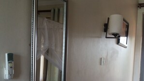 A hallway with a large mirror, a wall-mounted light fixture, and a visible power outlet. - Zawadi Hotel (Adjumani)