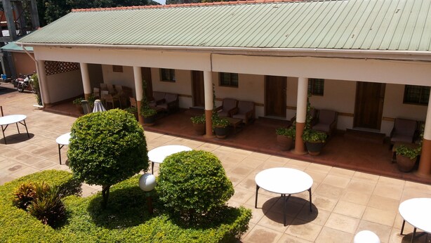 A covered outdoor seating area with tables and chairs, surrounded by potted plants and a tiled floor. - Zawadi Hotel (Adjumani)