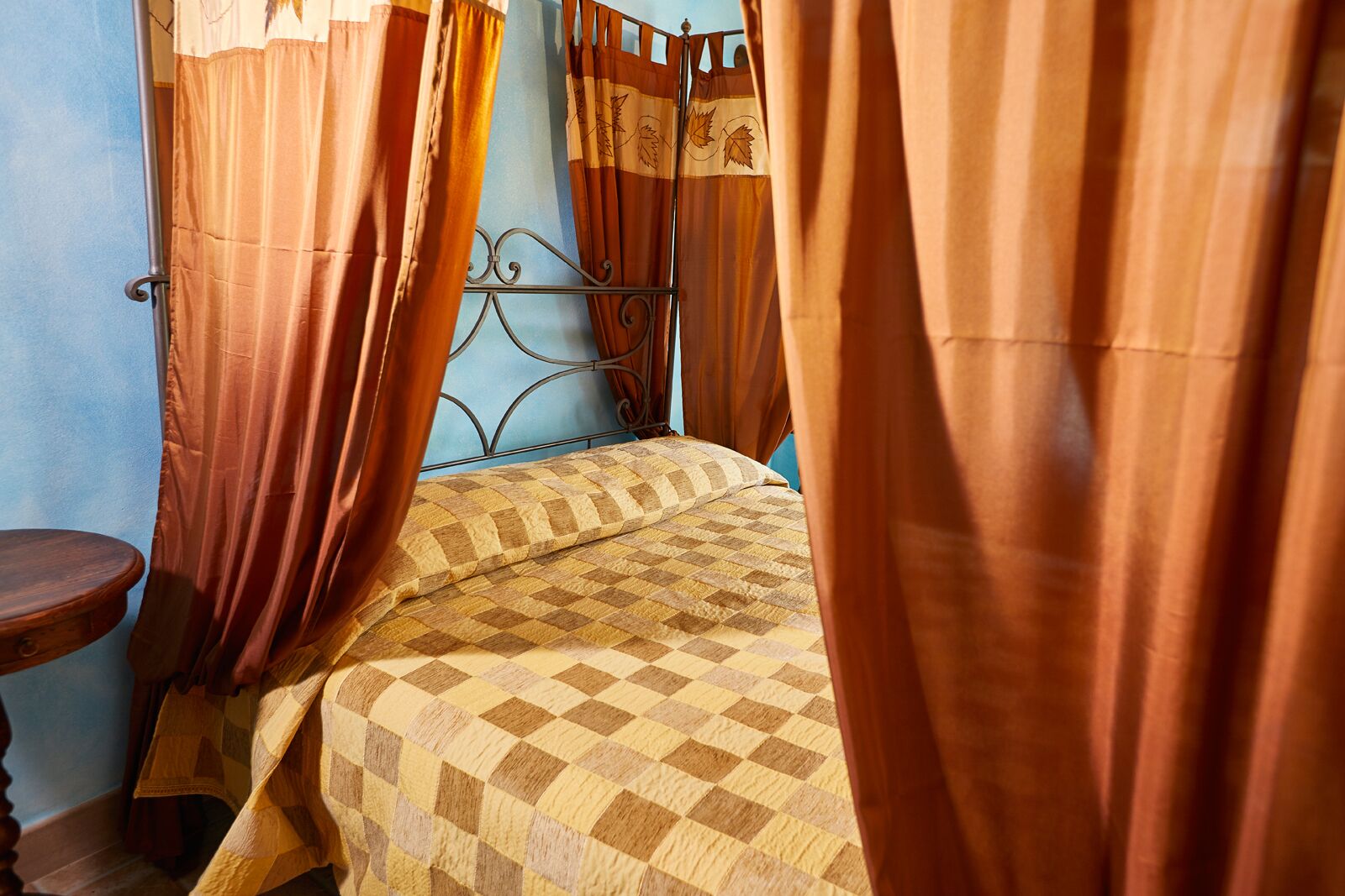 A bedroom with a checkered bedspread, a metal bed frame, and curtains.