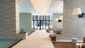 A modern lobby with a pool, seating areas, and a large glass entrance.