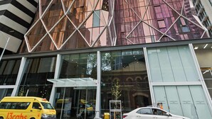 A modern building with a unique angular design, featuring a glass facade and a prominent entrance with a canopy.