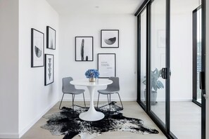 Simple, modern space with a round table, framed photographs, and a city view.