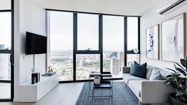 A modern living room with a large window, a flat-screen TV, a sofa, and a coffee table.