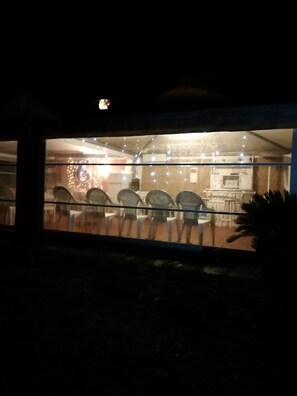 Una habitación con poca luz, con varias sillas dispuestas en filas, una mesa y un mostrador con una vitrina.
