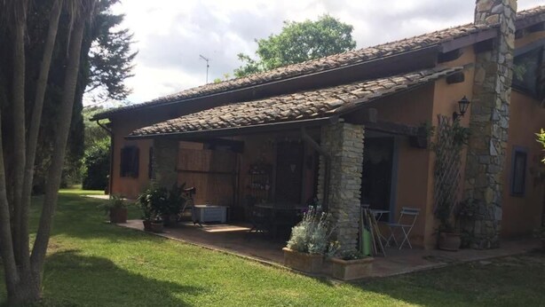 A rustic house with a stone facade, a tiled roof, and a covered patio area with outdoor furniture. - Casale Sant'Elia (Capranica)