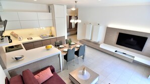 A modern living space with a kitchen, dining area, and a TV mounted on the wall. - Vila Ključe Apartments Bled (Bled)