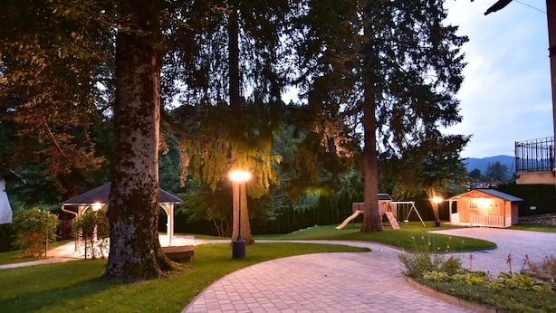 A paved pathway in a park with trees, a gazebo, and a small building with a porch. - Vila Ključe Apartments Bled (Bled)