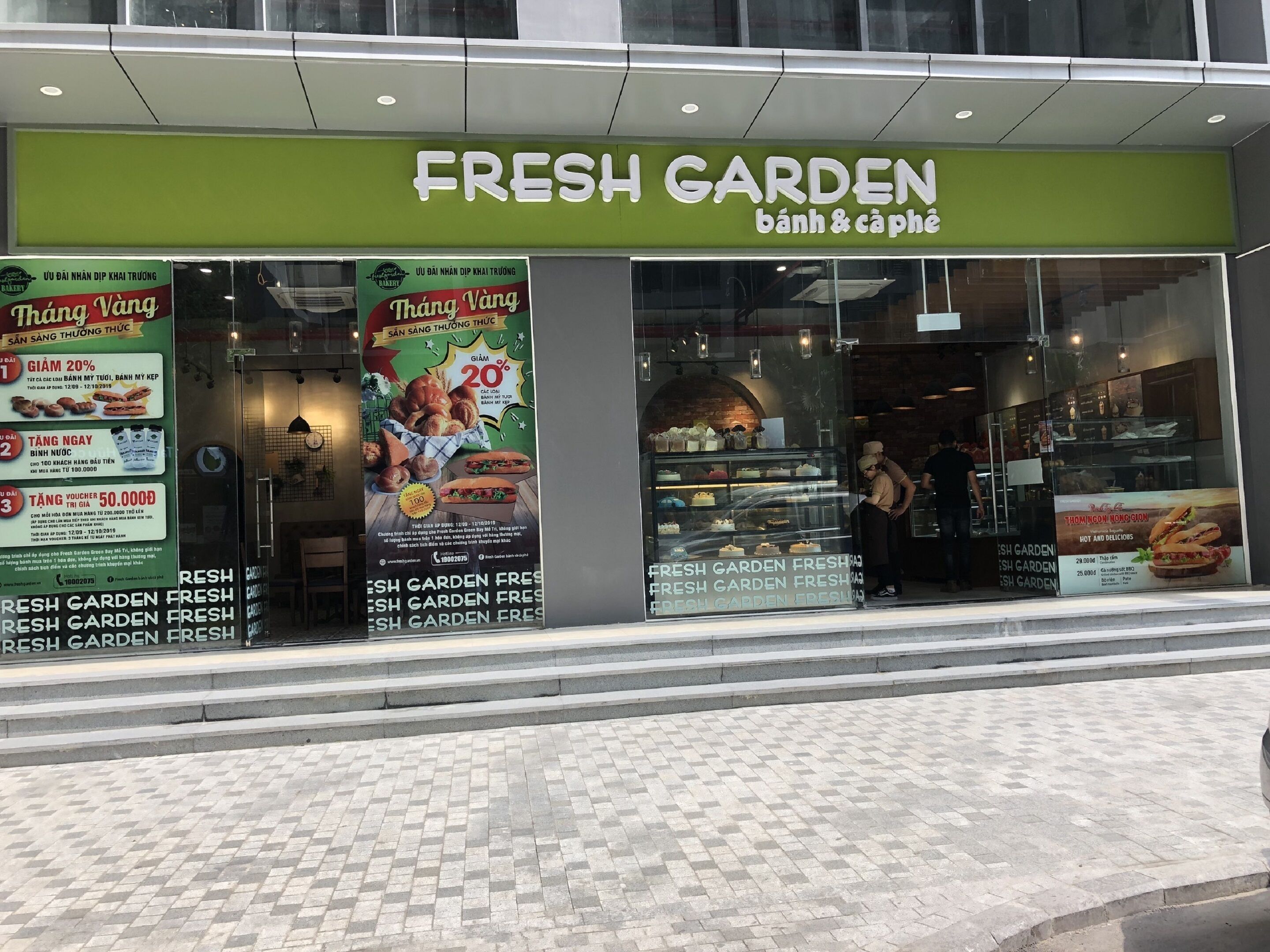 A storefront with a green sign reading "FRESH GARDEN bánh & cà phê".