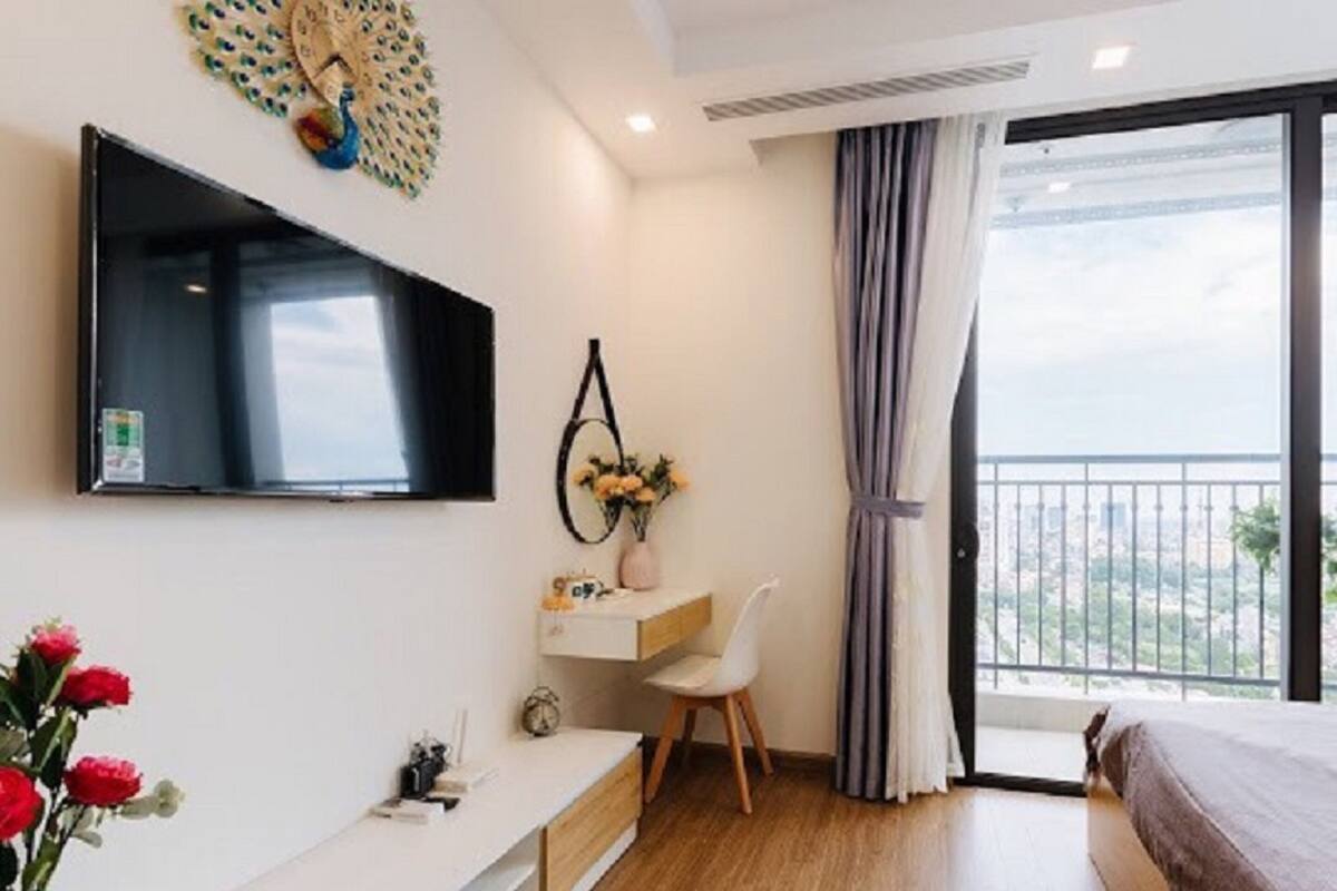 Een moderne hotelkamer met een flatscreen televisie, een bureau met stoel, een bed en een balkon met uitzicht over de stad.