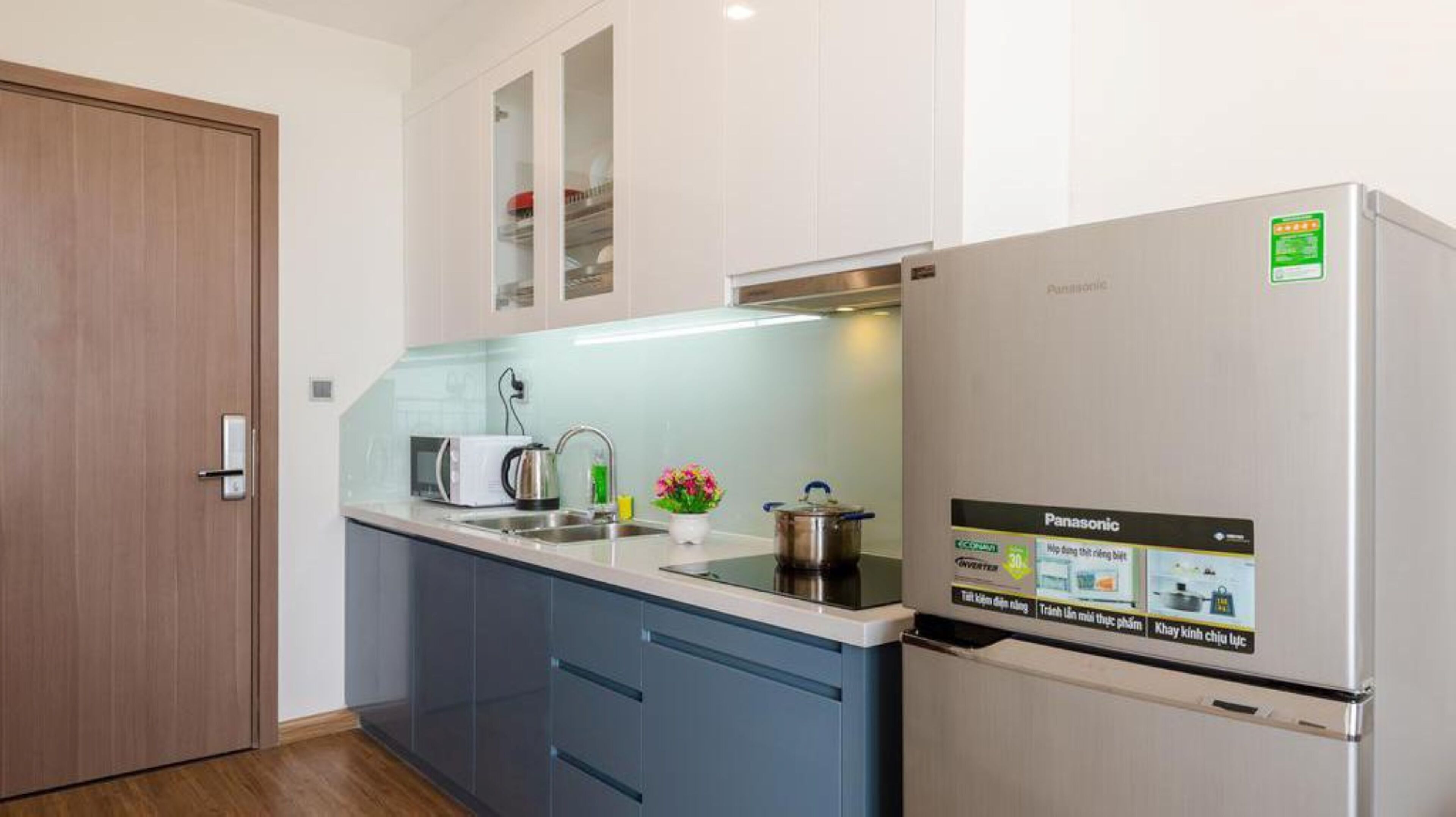 A compact kitchen with a refrigerator, microwave, sink, and cabinets.