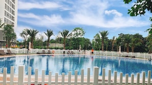 A swimming pool with a white fence, surrounded by palm trees and a white picket fence. - Vinhomes Green Bay Apartments (Hanoi)