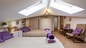 A modern hotel room with two beds, a sitting area with chairs, and skylights.