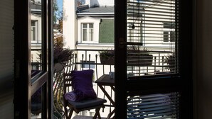 A balcony with a chair and a table, a door, and a view of buildings.