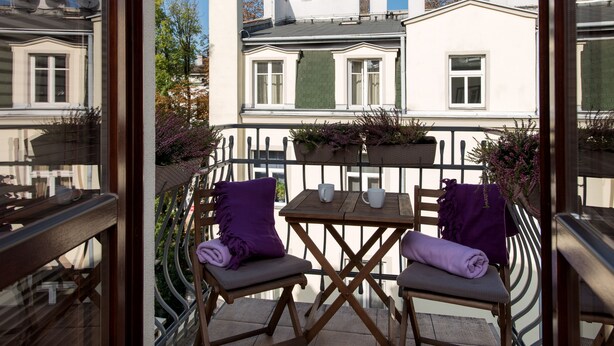 A balcony with two chairs, a table, and a potted plant.