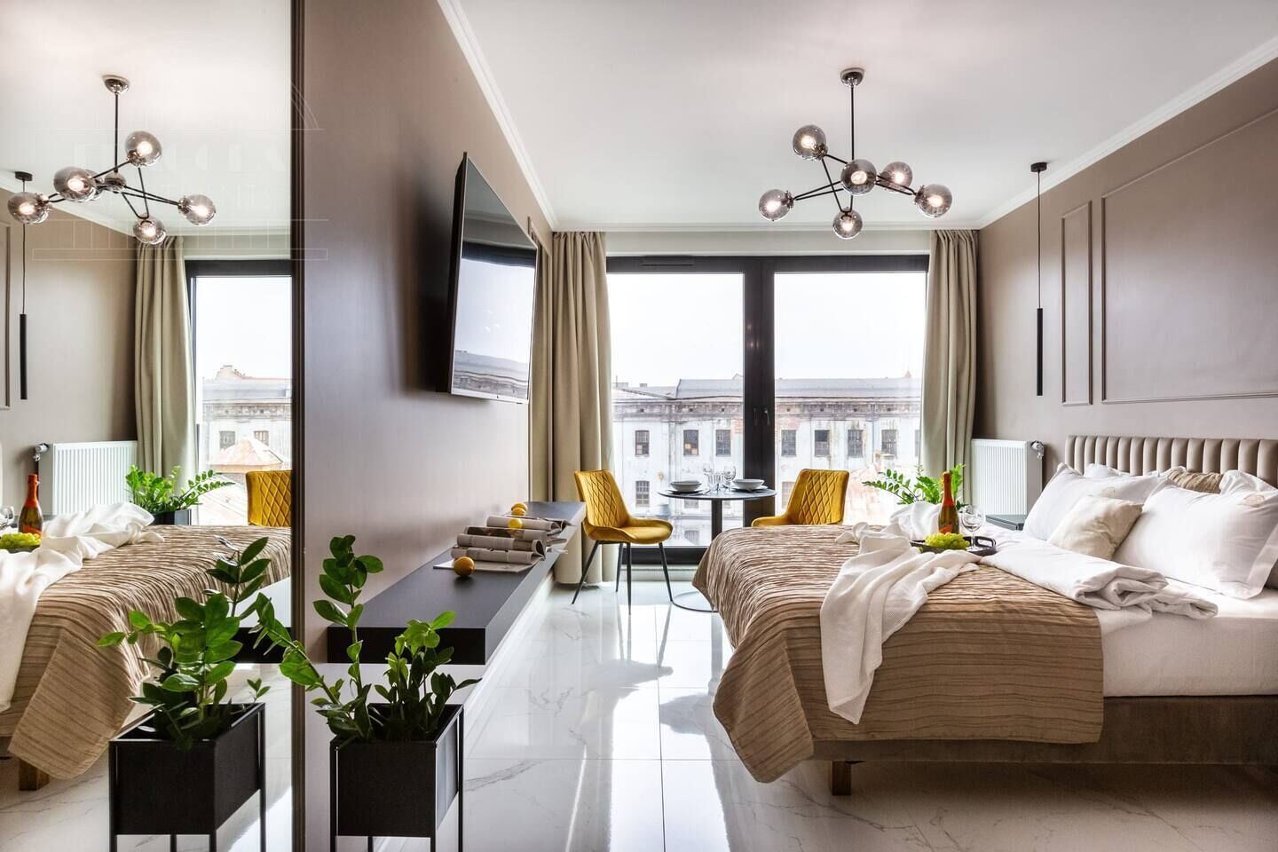 A modern hotel room with a bed, a desk, a chair, and a view of the city.
