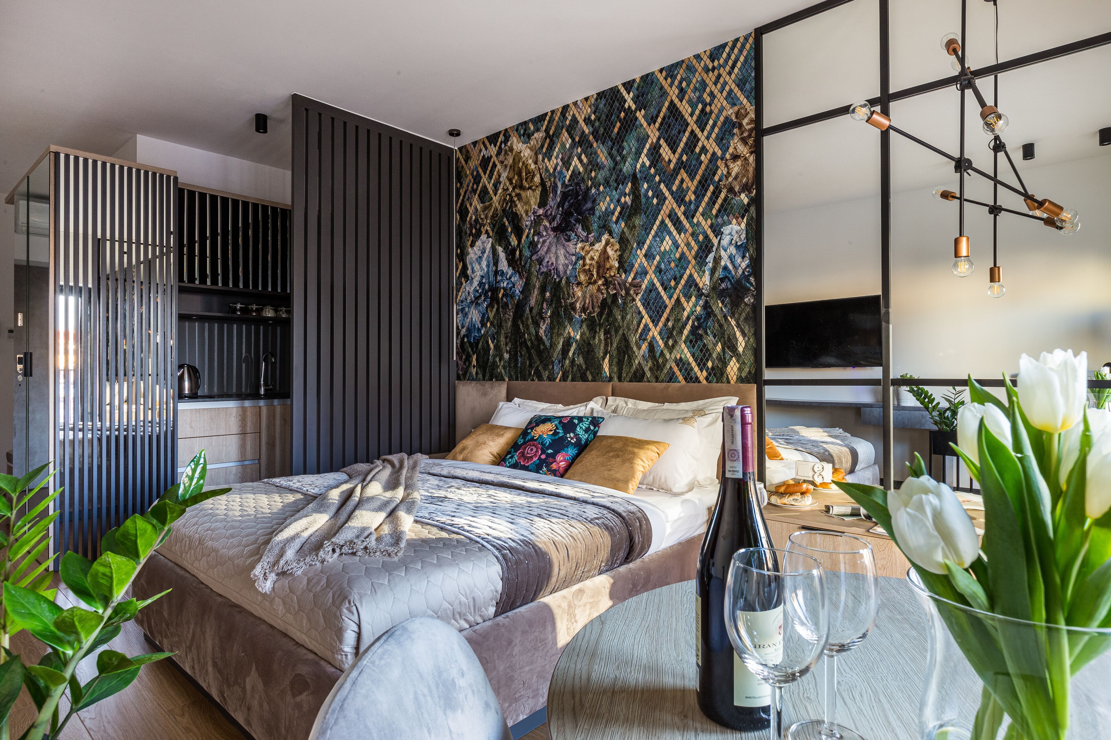 A modern bedroom with a bed, a nightstand, a wall-mounted TV, and a decorative wall pattern.