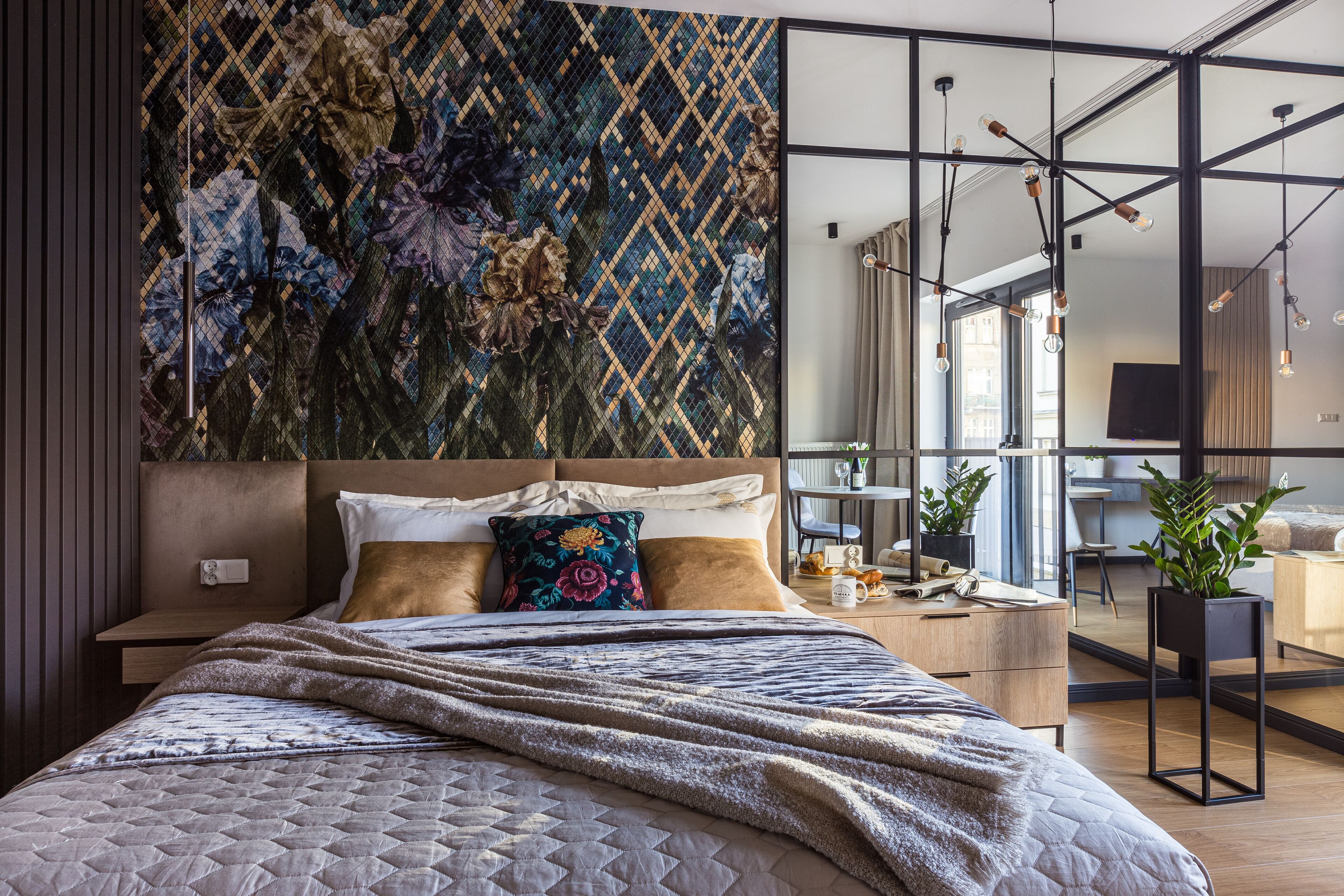 A modern bedroom with a large bed, a decorative wall, and a view of the city.
