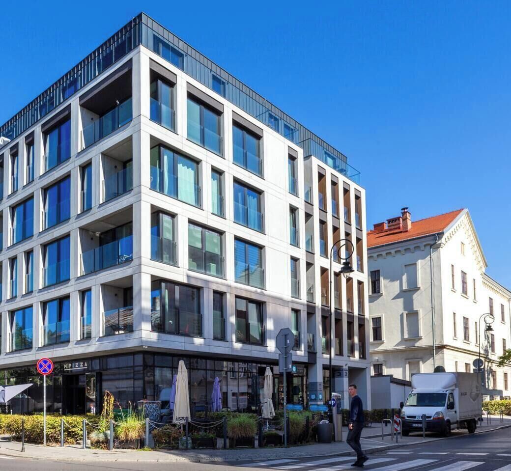 En modern byggnad med flera våningar, stora fönster, en synlig restaurang som heter ”NPizza” och en parkeringsplats.