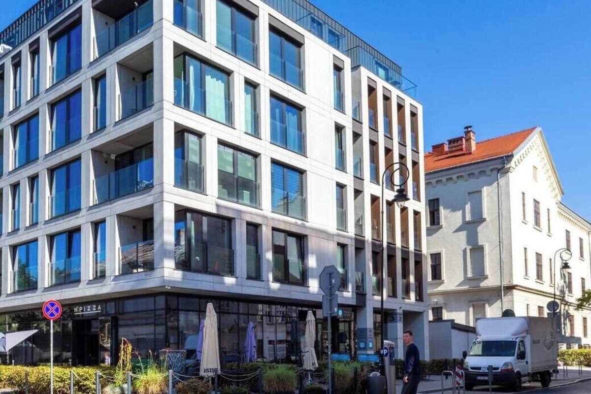 En modern byggnad med flera våningar, stora fönster, en synlig restaurang som heter ”NPizza” och en parkeringsplats.
