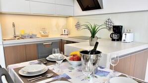 A modern kitchen with a dining area set for a meal. - Vila Ključe Apartments Bled (Bled)
