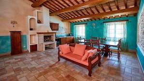 Une cuisine rustique avec une cheminée en briques, des meubles en bois et un coin repas comprenant une table et des chaises.