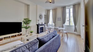 Ein modernes Wohnzimmer mit Flachbildfernseher, Kamin, einer Couch und einem Essbereich mit Tisch und Stühlen.