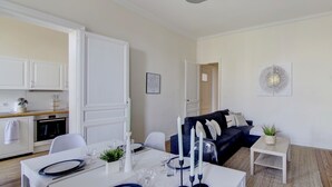 Ein modernes Wohnzimmer mit Essbereich, einem dunkelblauen Sofa und einem kleinen Tisch mit Kerzen.
