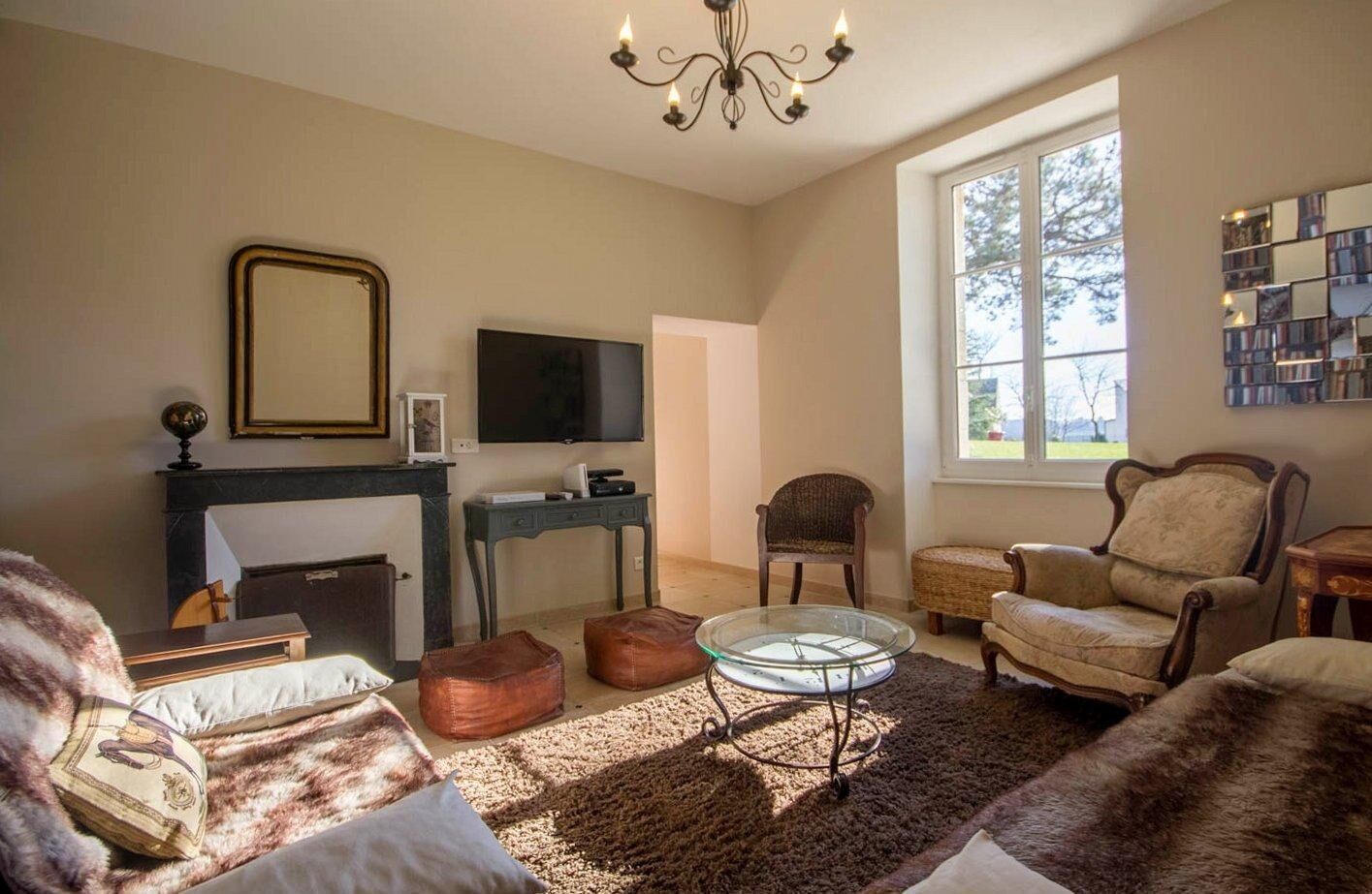 Een woonkamer met een open haard, televisie en comfortabele zithoek.
