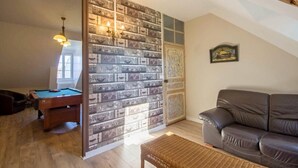 A cozy living room with a pool table, a leather sofa, and a wall decorated with vintage suitcases.