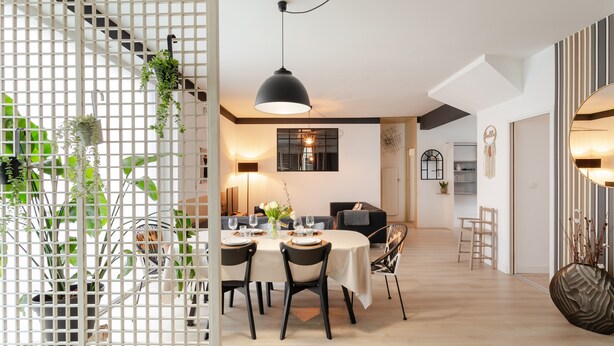 Un'area pranzo moderna con un tavolo rotondo, sedie e una lampada a sospensione.