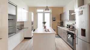 Una cucina moderna con isola centrale, elettrodomestici in acciaio inossidabile e un'ampia finestra che fa entrare luce naturale.