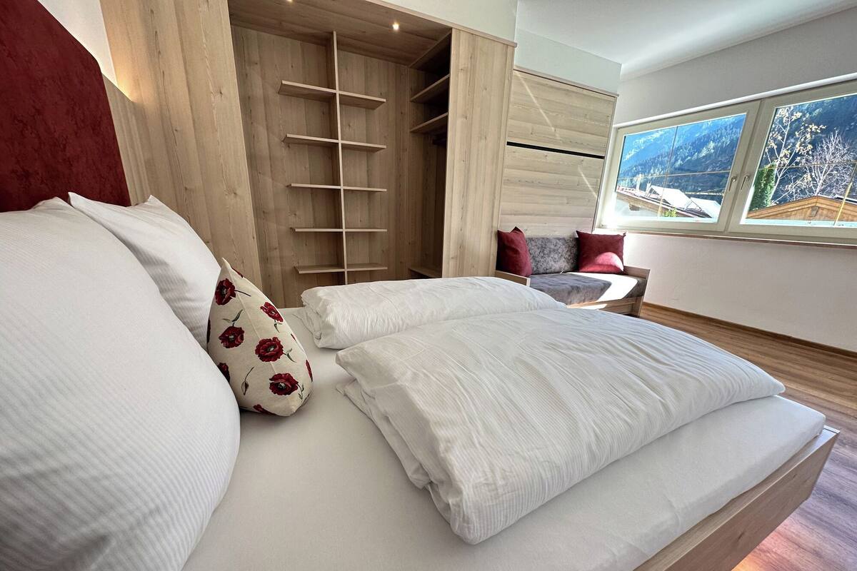 Une chambre à coucher avec un lit, une armoire en bois et une fenêtre donnant sur la montagne.
