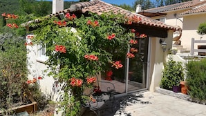 Una casa con jardín, patio y puerta de acceso al interior.