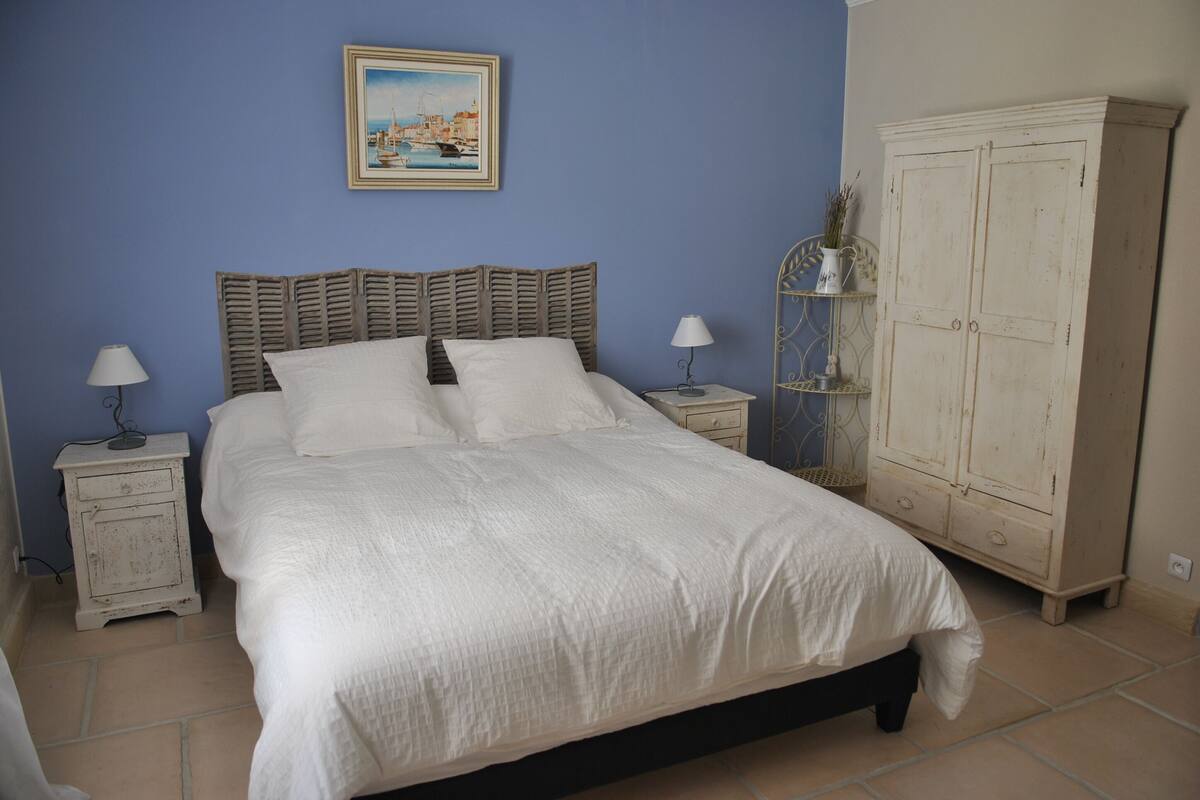 A bedroom with a bed, two bedside tables, a nightstand, a cabinet, and a painting on the wall.
