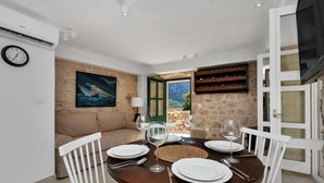 A dining area with a round table set for four, white chairs, and a view of the outdoors through a door.