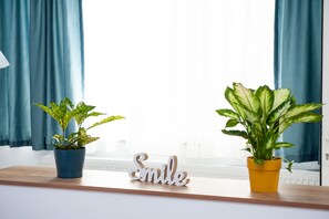 Plants and a cheerful sign adorn the shelf, offering a welcoming touch.