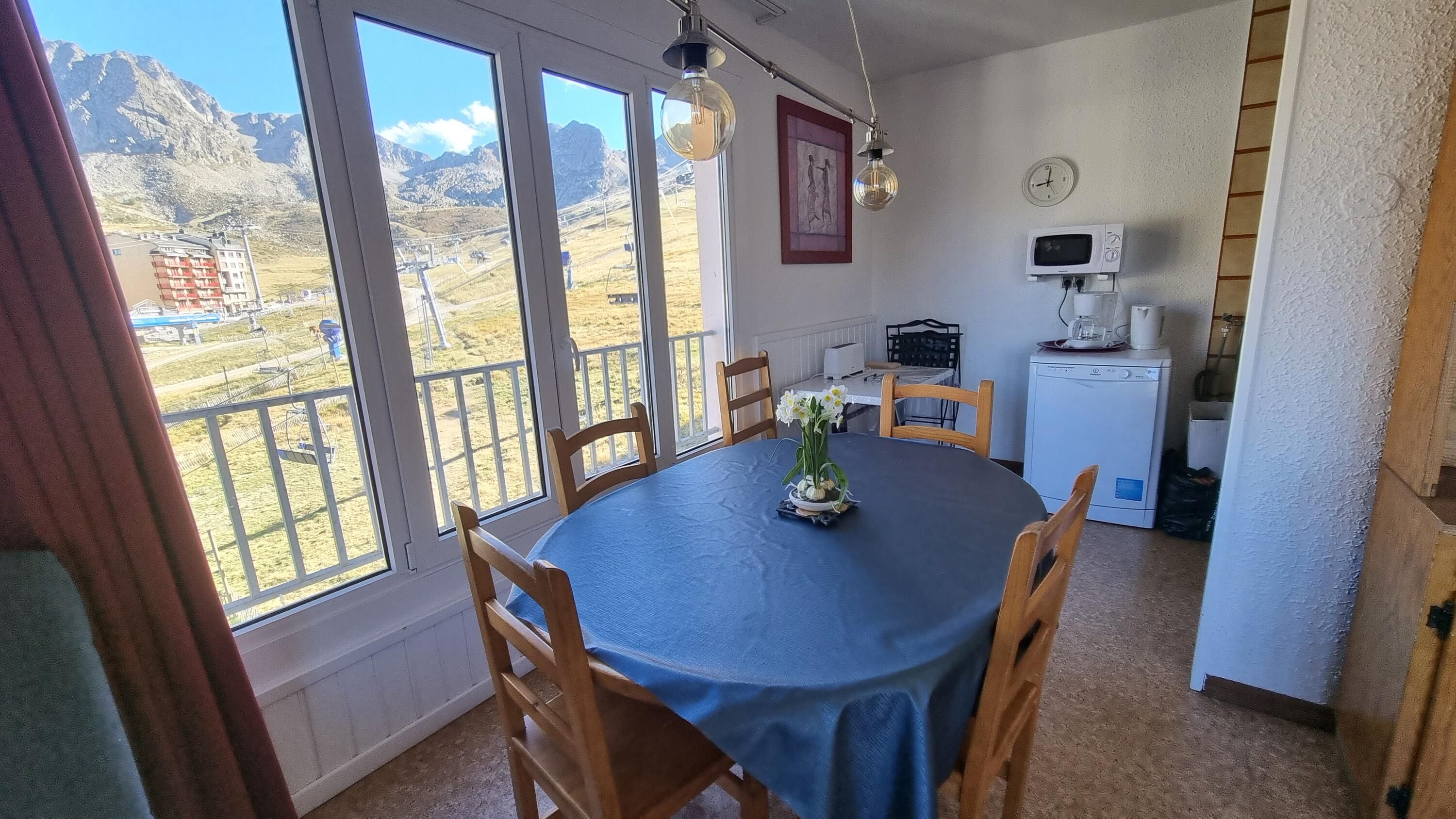 A dining area with a table, chairs, and a view of mountains through large windows.