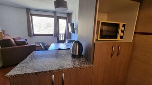 A compact kitchenette with a microwave, a kettle, and a small dining area with a table and chairs.