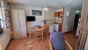 A compact living space with a dining area, kitchenette, and a television mounted on the wall.