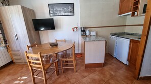 A compact kitchen with a dining table, chairs, a television, and a small refrigerator. - GRIZZLY 207- estudi-4 pers- 10m piste-Pas de la Casa -005846 (PAS DE LA CASA)