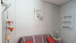 Ett rum med en säng, två sängbord, en hylla som är monterad på väggen och en vägglampa.