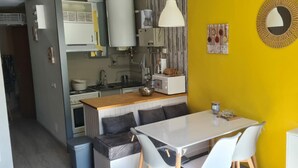 Una cucina compatta con zona pranzo, un tavolo bianco e un divano.