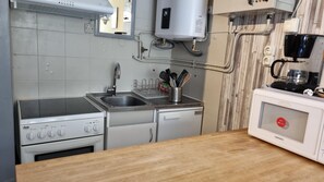 A kitchen with a stove, sink, and a coffee machine.
