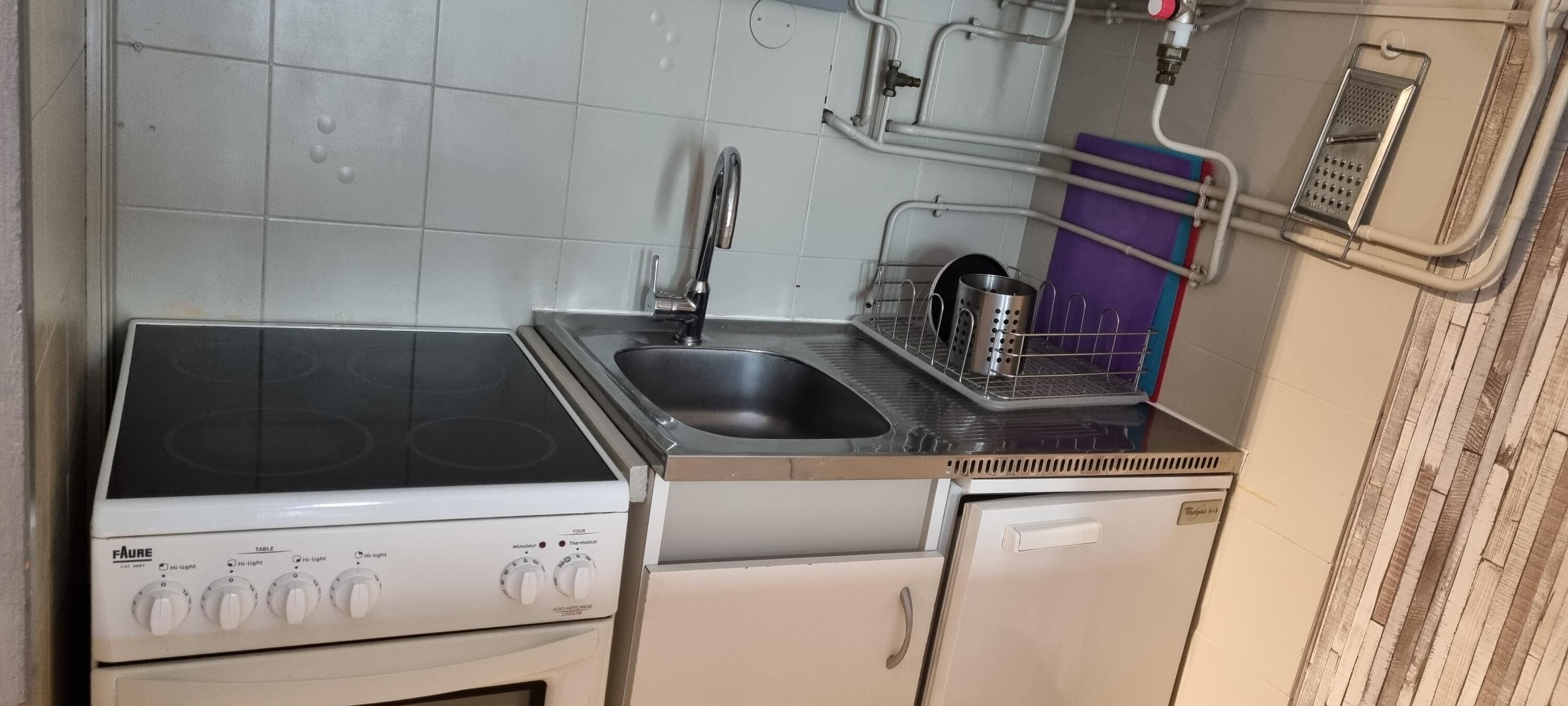 Eine kleine Küche mit Herd, Spüle und einem Kühlschrank.