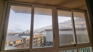 A room with a large window overlooking a mountainous landscape and a town below. - 505 SKY -Apt 1 hab- 4 pers-Pas de la Casa-10 m pistes -005632 (PAS DE LA CASA)