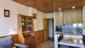 A cozy kitchen with wooden cabinets, a dining table with a chandelier, and a built-in oven. - 505 SKY -Apt 1 hab- 4 pers-Pas de la Casa-10 m pistes -005632 (PAS DE LA CASA)