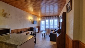 A cozy kitchen with a microwave, wooden cabinets, and a dining area with a table and chairs. - 505 SKY -Apt 1 hab- 4 pers-Pas de la Casa-10 m pistes -005632 (PAS DE LA CASA)